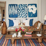 A living room with a Mimosa Cyanotype couch by John Robshaw and striped rug, adorned with exotic palms. - 29550136819758