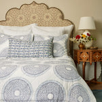 A Quilts & Coverlets hand quilted bed with a Lapis Quilt blue and white patterned comforter made of cotton voile. - 29588922531886