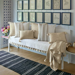 A bench with Woven Sand Kidney Pillows by John Robshaw and framed pictures. - 30009679380526