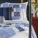 A bed with John Robshaw Gent Stripe Mini Round Bolster quilts and pillows. - 30009708642350