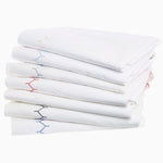 A stack of Stitched Blush Organic Sheets from Sheets & Cases with embroidered blue and red stitching. - 28739511648302