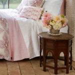 A bed with a pink comforter and pink pillows featuring John Robshaw's Natural Bone Inlay Table. - 29554011701294