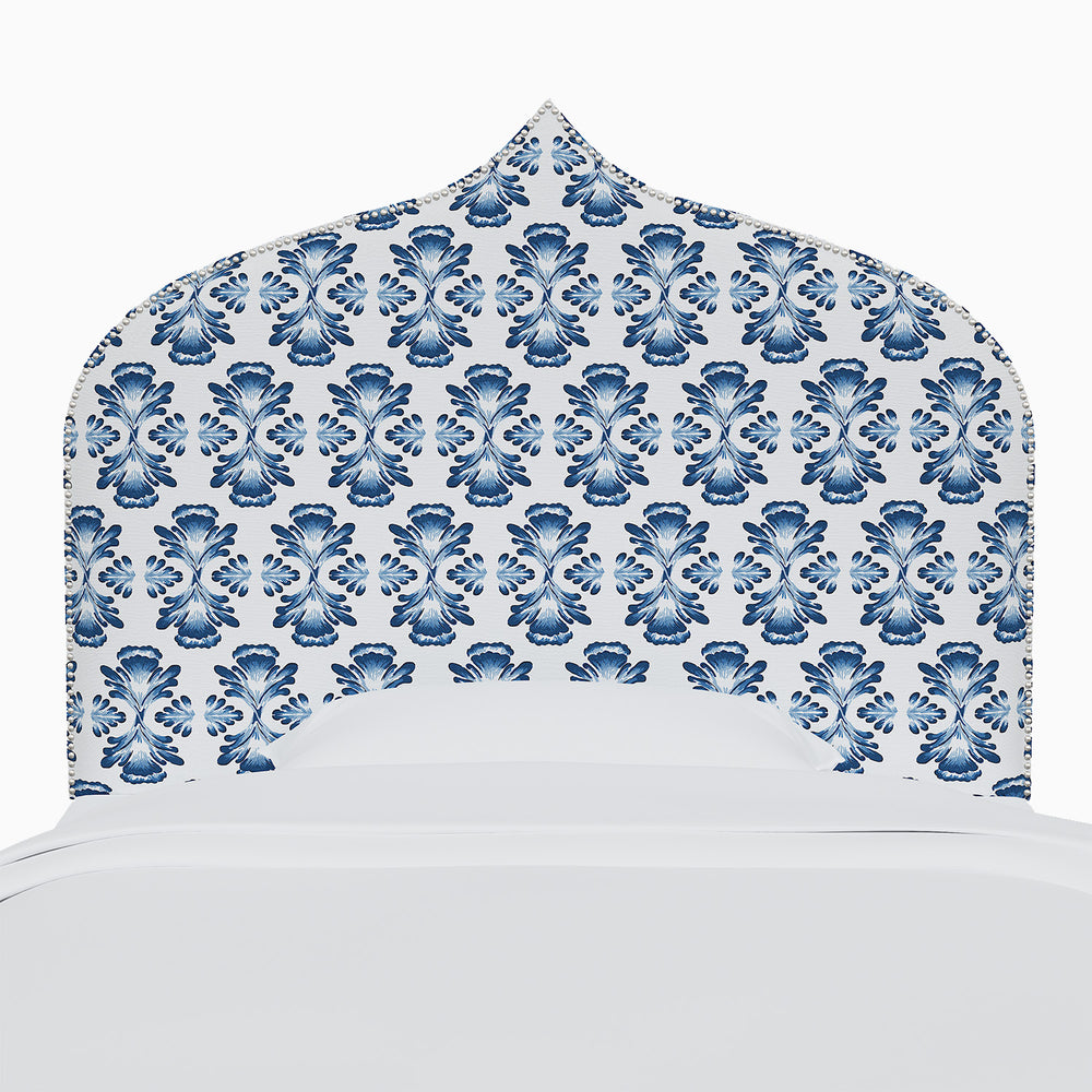 A bed with a blue and white patterned John Robshaw Alina Headboard.