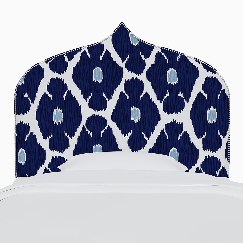 A bed with a blue and white John Robshaw Alina Headboard featuring Mughal arches prints.