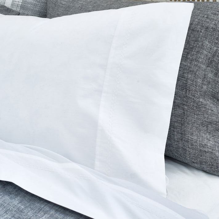 An image of a bed with John Robshaw's Anketi White Organic Sheet Set and pillows.