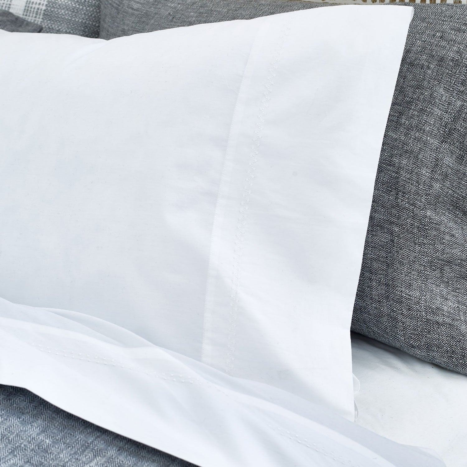 An image of a bed with John Robshaw's Anketi White Organic Sheet Set and pillows.
