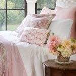 A bed with Stitched Blush Organic Sheets by Sheets & Cases and flowers. - 28807124975662