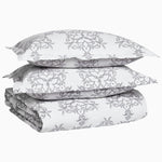 A stack of Kajal Gray Organic Duvet pillows, made with organic cotton, by John Robshaw and are in a grey and white pattern. - 29980994306094