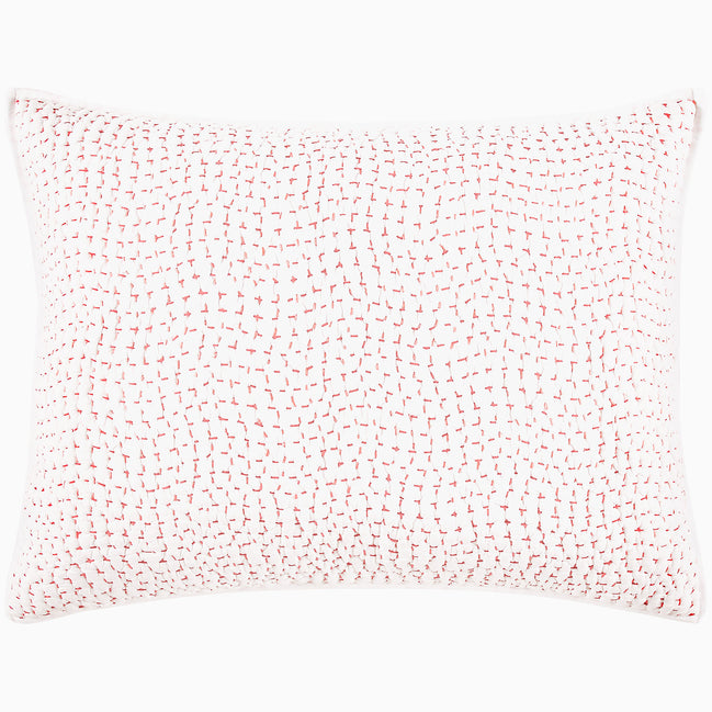 A John Robshaw Organic Hand Stitched Lotus Quilt with a pink and white pillow with dots on an organic cotton voile coverlet.