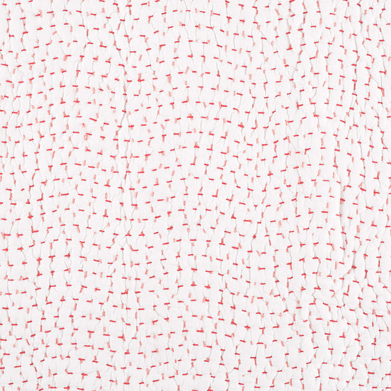 A white background with red and white dots on it. Additionally, the Organic Hand Stitched Lotus Quilt Swatch by John Robshaw features hand-stitched details and is reversible.