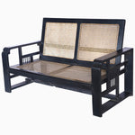 A vintage John Robshaw black loveseat with curved arms and a rattan seat. - 29225384017966