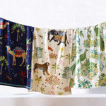 Four Dhule Indigo Beach Towels by John Robshaw hanging on a line with animals on them, made of 100% cotton. - 29274374537262