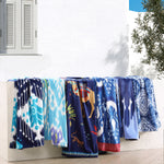 A row of Dhule Indigo Beach Towels made of 100% cotton, hanging on a wall next to a window. (Brand Name: John Robshaw) - 29274375192622