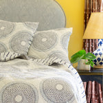 A John Robshaw Lapis Quilt, a vintage woodblock-inspired blue and white comforter with a handcrafted look on a bed. - 15636202749998
