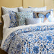 A bed with blue and white Layla Azure Quilt bedding by John Robshaw and a butterfly pillow.