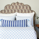 A bed with John Robshaw's Vintage Stripe Indigo Lumbar Pillow printed blue and white bedding and pillows. - 30264084135982