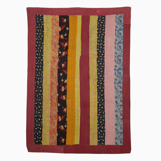 A John Robshaw Sit Up Please quilt hanging on a wall in India.