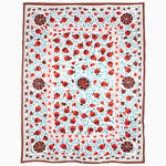 An embroidered Seaglass Suzani Blanket with ladybugs on a blue and red Vintage Blankets rug. - 30265246810158