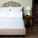 A white bed with an ornate headboard made of John Robshaw's Organic Hand Stitched Sand Quilt.
