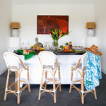 An Umida Ikat Black Beach Towel-inspired table adorned with chairs and complemented by a stylish hat by John Robshaw. - 15419314405422