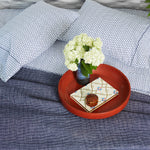 A Kesar Indigo Organic Sheet Set by Sheets & Cases with a flower on it on a bed made of organic cotton. - 28311597514798