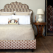 A bed with a patterned headboard adorned with John Robshaw's Vivada Sand Woven Quilt coverlets.