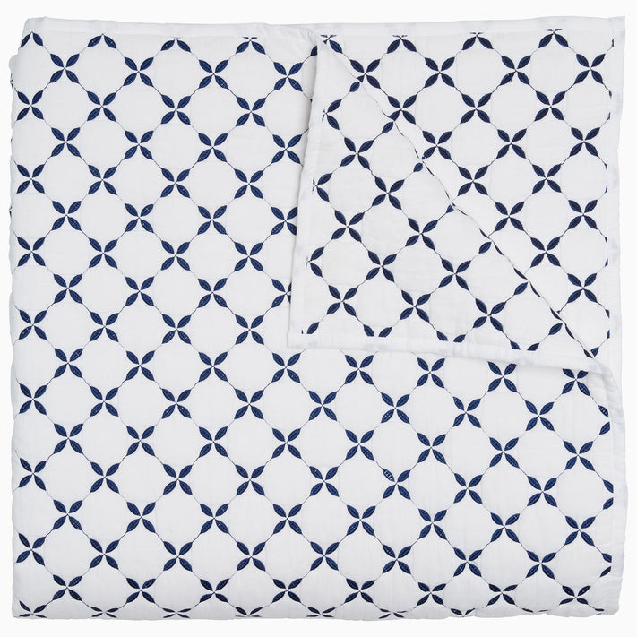 A blue and white Layla Indigo Quilt blanket with a cross design by John Robshaw.