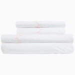 An embroidered stack of Stitched Blush Organic Sheets with pink piping by Sheets & Cases. - 28765998579758