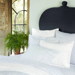 A bed with blue, white, and Vamika Periwinkle Organic Sheets made of organic cotton by John Robshaw. - 28783118581806