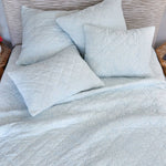 A bed with the Quilts & Coverlets Sagana Light Indigo Quilt and hand quilted diamonds pillows. - 28783138963502