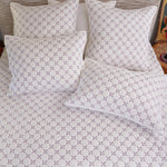 A bed featuring a Layla Lavender Quilt by John Robshaw, adorned with matching pillows. - 28783173369902
