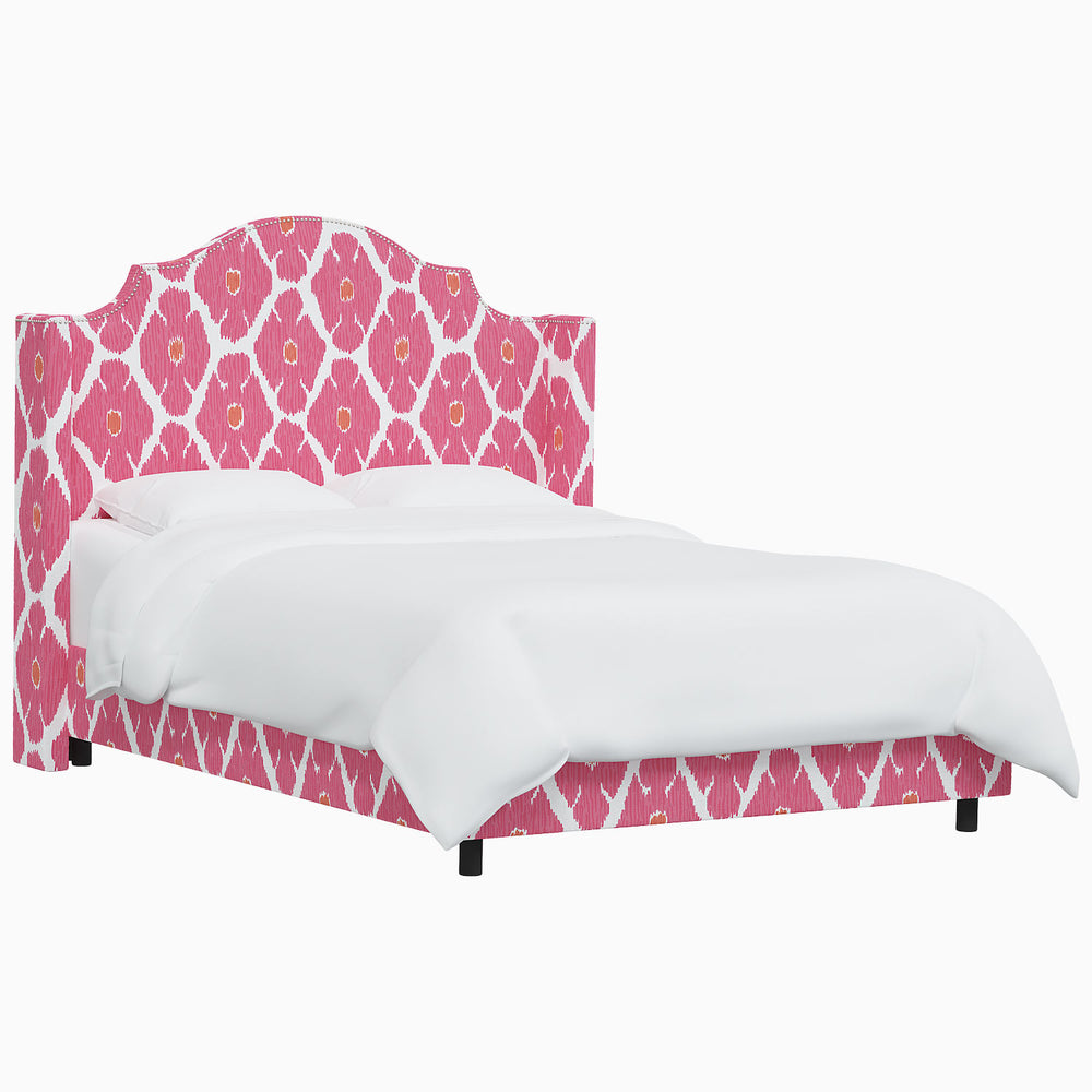 The John Robshaw Samrina bed, featuring a pink upholstered frame and a white headboard, exudes elegance and sophistication reminiscent of John Robshaw's Mughal arches designs.