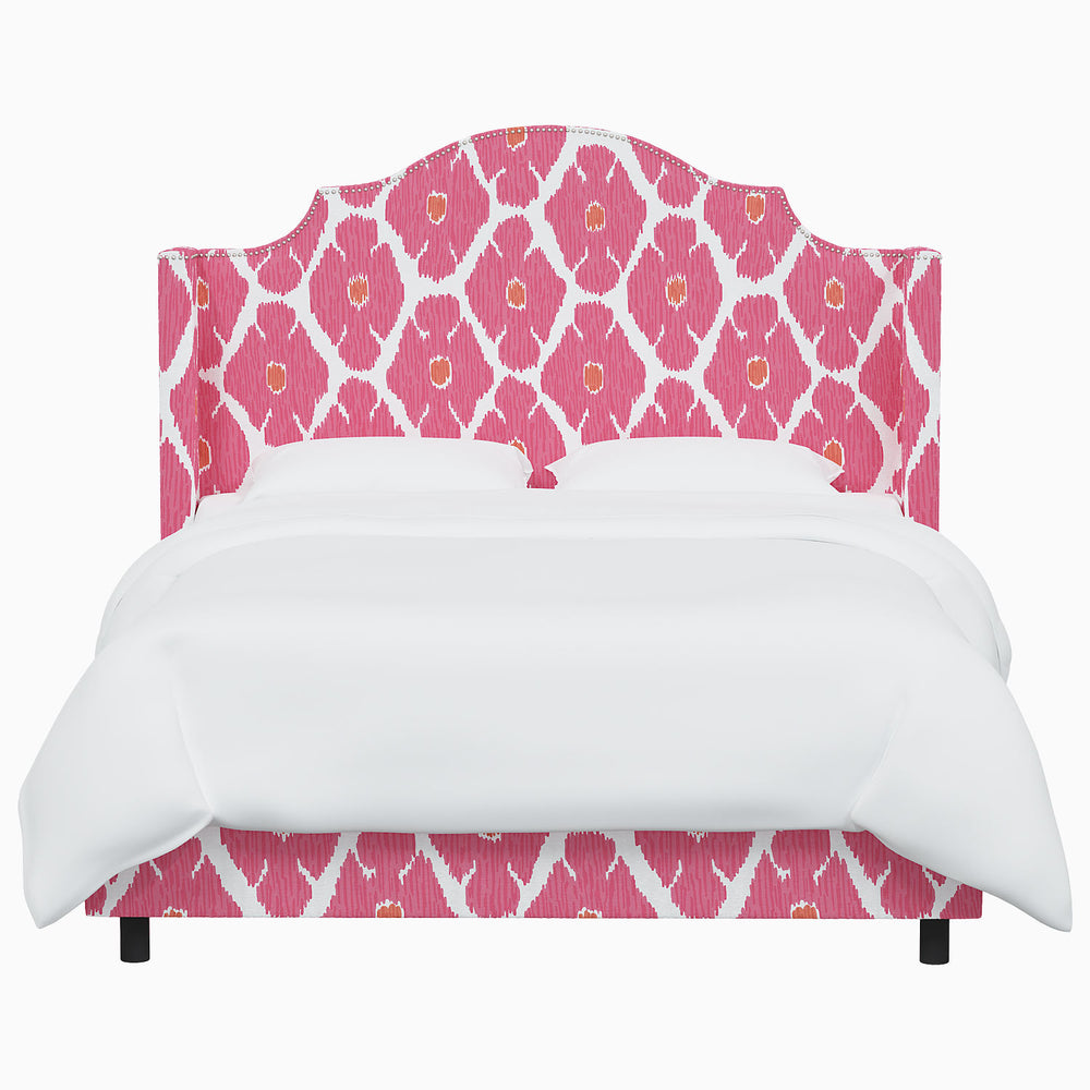A John Robshaw Samrina bed with a pink and white patterned headboard.