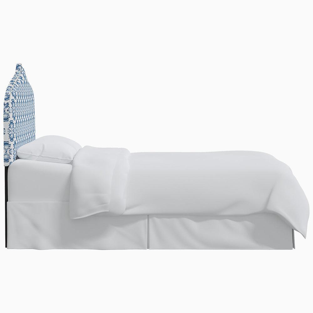A white bed with a blue John Robshaw Alina headboard.