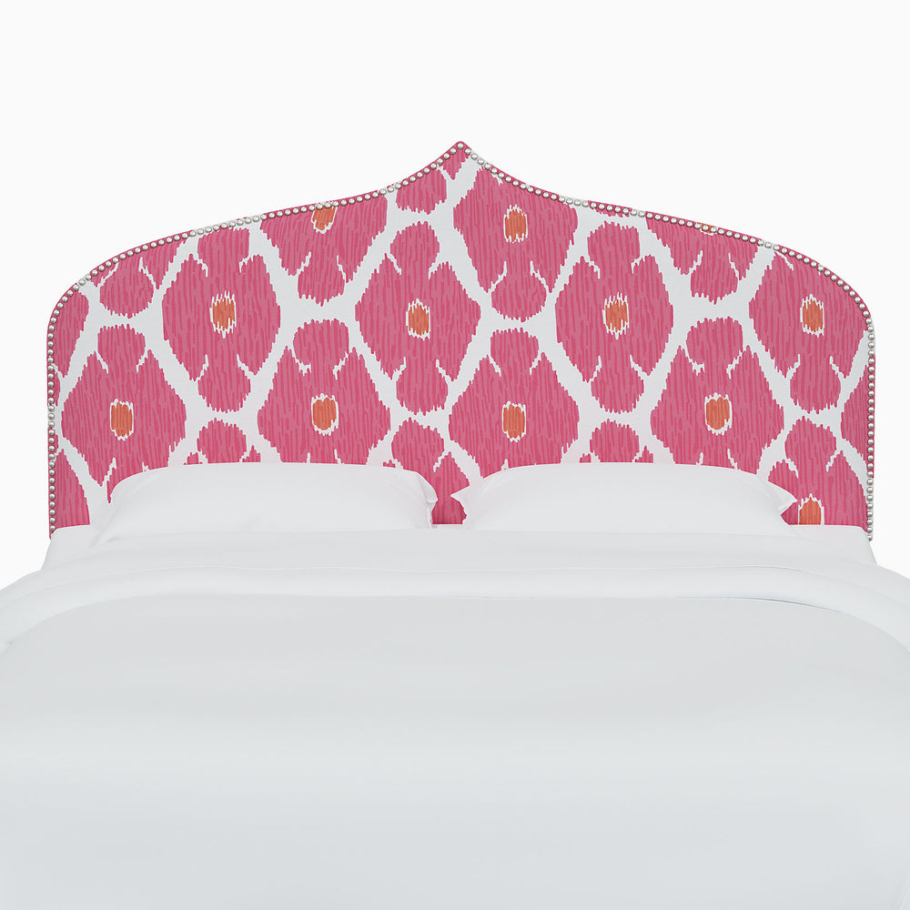 A bed with a pink and white John Robshaw Alina Headboard.