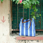 A blue and white Vintage Stripe Tote Bag by John Robshaw sitting on a window sill. - 6601741336622