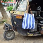 A Vintage Stripe Tote Bag by John Robshaw, a blue and white striped tote bag, attached to a tuk tuk. - 6601742614574