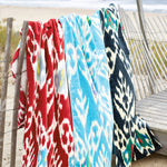A vibrant collection of John Robshaw Umida Ikat Blue Beach Towels from Uzbekistan displayed on a fence. - 5797416828974