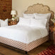 A John Robshaw Custom Bihar Bed with an ornate headboard, covered in fabric, in a bedroom.