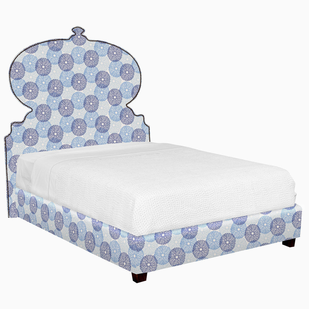 A Custom Orissa Bed with a blue and white patterned headboard available for white glove delivery.